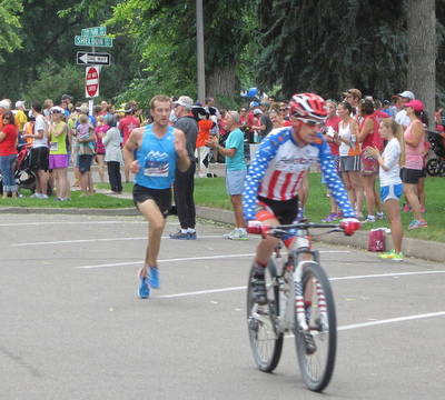 Cyclist riding in front of the leader of the 2014 FireKracker 5k Elite Race.